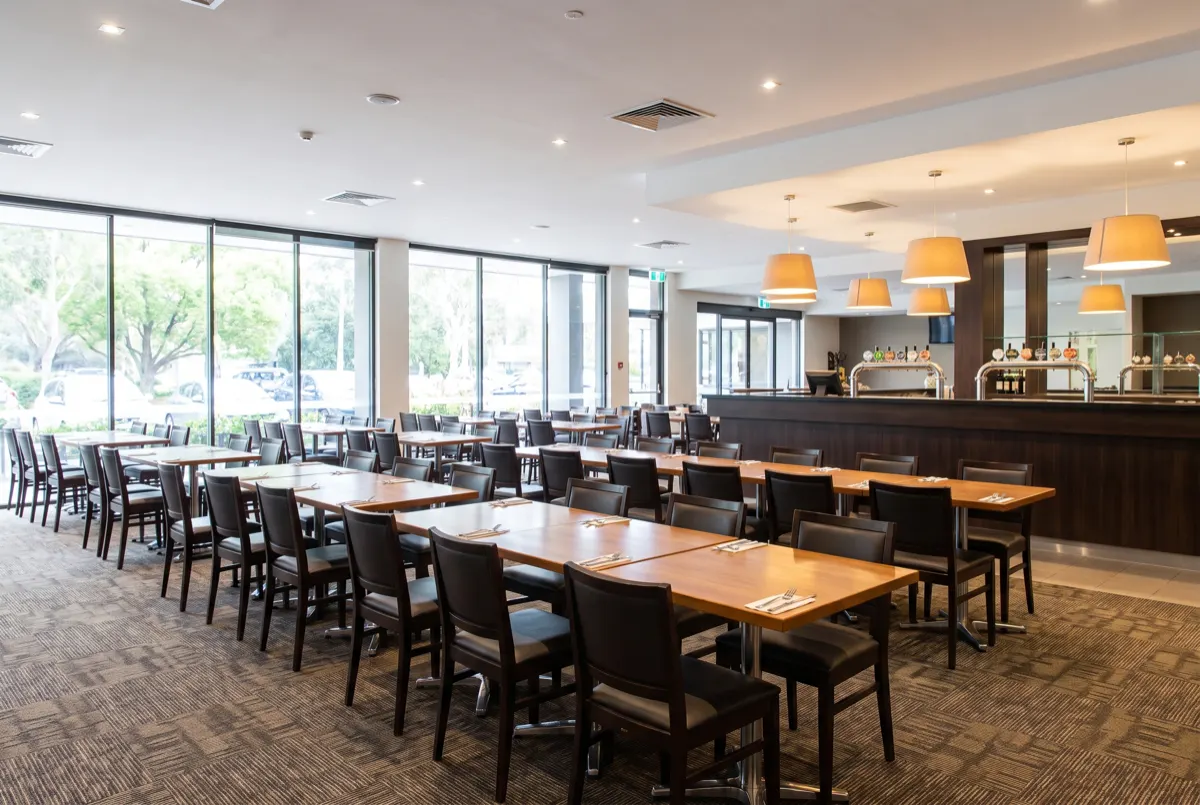 Clean, empty club bistro with tables set and a bar in the background
